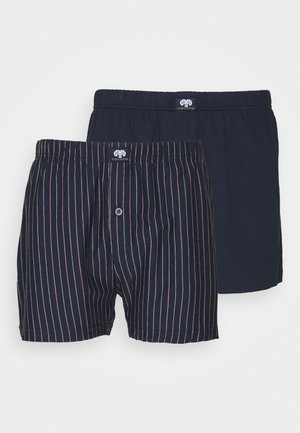 Twee paar herenboxers: één in effen marineblauw, de ander met marineblauw en dunne rode verticale strepen. Beide hebben elastische taillebands en een knoopgulp.
