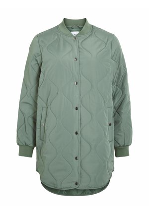 Polsterēta bumbvedēja jaka mīkstā zaļā krāsā ar viļņotu šūtu tekstūru, spīļu pogām, ribveida aprocēm un sānu kabatām ar apaļu apakšu.