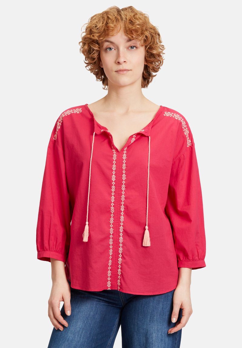 Rote Baumwollbluse mit V-Ausschnitt, Dreiviertelärmeln, cremefarbener dekorativer Stickerei entlang der Schultern und in der Mitte, verstellbaren Bändern mit Quasten.