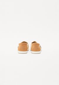 Baskets basses en suède tan et toile crème avec un bout rond et un logo embossé sur le talon. Semelle en caoutchouc et détails cousus.