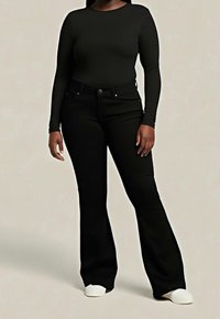 Černý top s dlouhým rukávem v kombinaci s černými rozšířenými džínami; oba z hladké látky. Bílá balerína doplňuje outfit.