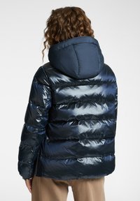 Chaqueta acolchada en azul marino con capucha desmontable, que presenta un acabado brillante, costuras horizontales y puños elásticos para brindar calidez y comodidad.