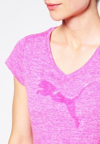 V-ringad, kortärmad sporttröja i livfull rosa melerat tyg. Har en diskret logotyp i en mörkare rosa nyans. Texturerad yta, figursydd design.