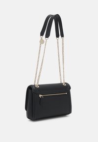 Černá kabelka se zlatými řetízkovými doplňky, kapsou na zip, texturovaným materiálem a strukturovaným designem; má dvojité popruhy pro větší všestrannost.