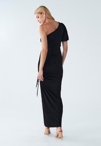 Schwarzes Ein-Schulter-Kleid mit taillierter Passform, seitlichem Raffung und einem hohen Schlitz bis zum Oberschenkel. Hergestellt aus weichem, strukturiertem Stoff und mit verstellbaren Bändern ausgestattet.