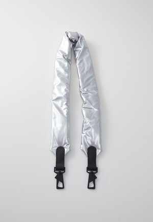 Sangle de sac rembourrée argentée avec extrémités en cuir noir et fermoirs métalliques sur fond gris clair.