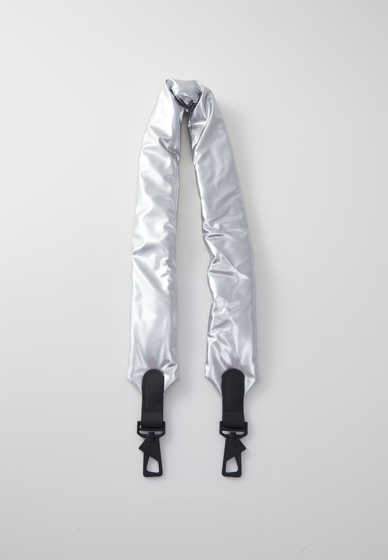 Sangle de sac rembourrée argentée avec extrémités en cuir noir et fermoirs métalliques sur fond gris clair.