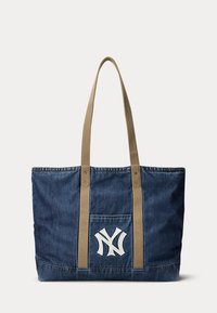 Traper torba za nošenje s bež remenjem za ramena i prednjim džepom na kojem je bijeli isprepleteni NY logo.