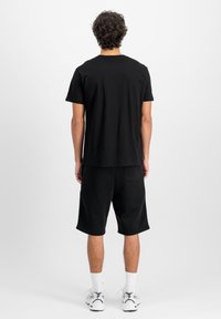 Sæt bestående af en sort bomulds t-shirt og shorts, med rund halsudskæring, korte ærmer og løs pasform. Udsmykket med en baglomme på shortsene.