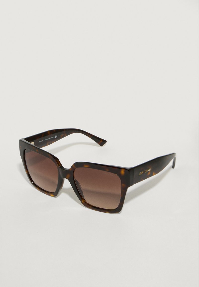 Lunettes de soleil en écaille de tortue avec des verres carrés et une teinte brune dégradée. Finition brillante, branches fines et détail du logo sur la monture.