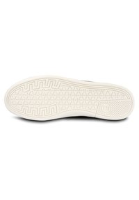 White rubber shoe sole featuring a textured grip pattern with geometric shapes and branding detail, designed for traction and durability.
