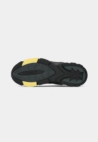 Shoe sole with black and yellow tread, textured grip, and "Lacoste" brand embossed in the center of the sole.
