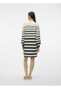 Abito a righe in crema e nero, con maniche lunghe, una vestibilità rilassata e dettagli a coste sul colletto e sui polsini.