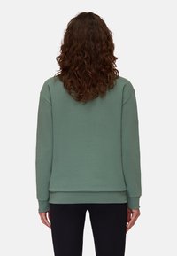 Zielona bluza z luźnym krojem, długimi rękawami oraz ściagaczami przy mankietach i dolnym brzegu. Gładka faktura, bez widocznych wzorów lub grafik.