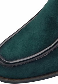 Zielone zamszowe buty z gładkim czarnym skórzanym wykończeniem. Projekt jest smukły, z zaokrąglonym noskiem i kontrastującym przeszyciem wzdłuż krawędzi.