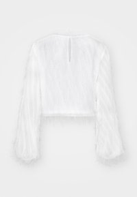 Vit kort topp med långa ärmar. Tillverkad av ett texturerat, fluffigt material. Har en nyckelhålsöppning bak och en odekorerad design.