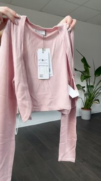 Világos rózsaszín, bordázott cropped kardigán hosszú ujjakkal. Kerek nyakkivágással, mellékelt címkékkel és sima textúrával rendelkezik.