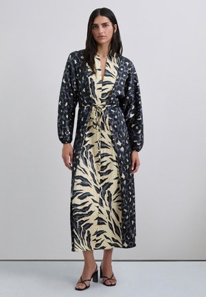Vestido largo estilo envolvente en negro y beige, con estampados de animales, cinturón en la cintura y mangas abullonadas. Textura de tela suave.
