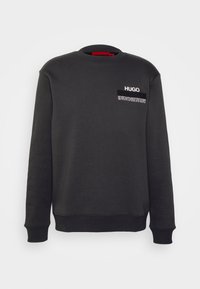 Schwarzer Sweatshirt mit Rundhalsausschnitt, langen Ärmeln, gerippten Bündchen und Saum sowie "HUGO"-Logo mit kleinem Text auf der oberen linken Brust.