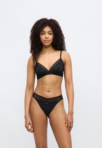 Black lingerie set featuring a lace-trimmed bralette with adjustable straps and matching low-rise panties with scalloped edges and a bow detail.