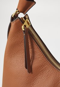 Braune Lederhandtasche mit strukturierten Oberflächen, goldenem Reißverschluss und schwarzem Akzent an der Oberseite. Verfügt über einen Reißverschlussverschluss zur Sicherheit.