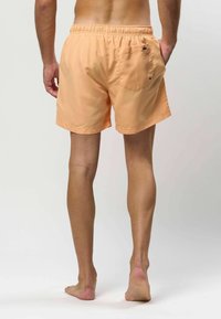 Mannen zwemshorts in pasteloranje. Elastaan tailleband, achterzak met knoopsluiting, losse pasvorm en een gladde stof textuur.