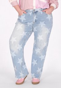 Jeans in denim azzurro chiaro con un motivo a stelle sbiadito, dal fit rilassato, tasche frontali e orlo strappato, abbinati a scarpe rosa.