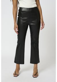 Svarta, fusk läderbyxor med utsvängda ben, slät yta, hög midja och sydda detaljer vid knäna. Matchas med svarta klackar med remmar.