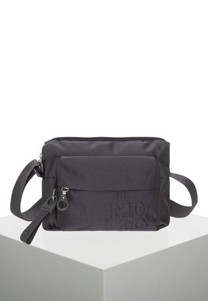Sac bandoulière noir compact en tissu texturé, poche avant zippée, sangle réglable et logo embossé en bas à droite.