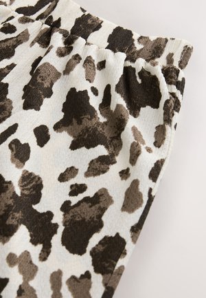 Tessuto animalier marrone e crema, caratterizzato da una superficie texturizzata con grandi forme irregolari, vita arricciata e aspetto morbido.