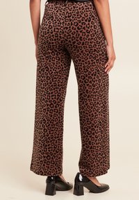 Bruin en zwart corduroy met panterprint wijde broek, met een hoge taille en zijzakken, gecombineerd met zwarte hakken.