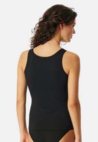 Zwarte mouwloze tanktop met een aansluitend ontwerp, gemaakt van zachte stof. Beschikt over een ronde halslijn en subtiele gestikte details aan de zoom.