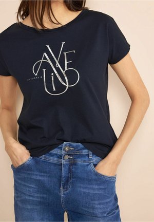 Marineblå t-shirt med korte ærmer og rund halsudskæring; har sølvfarvet grafisk tekst "AVE LI", parret med denim jeans.