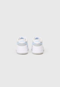 Pár bílých a světle modrých tenisek Nike zobrazených zezadu na jednolitém světlém šedém pozadí.