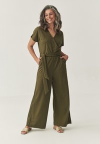 Olivengroene jumpsuit met korte mouwen, met een wikkeldesign, een strikceintuur in de taille, zijzakken en een wijde pijpen silhouet. Gladde stofstructuur.