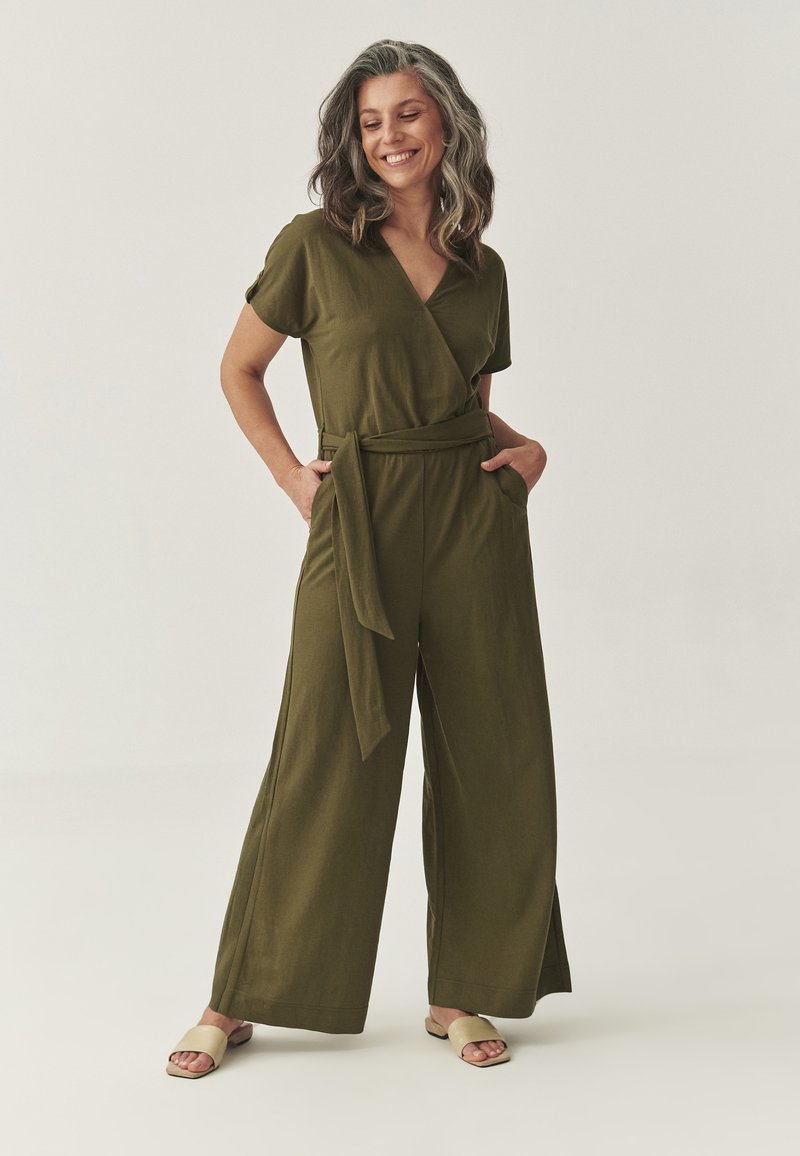 Olivengroene jumpsuit met korte mouwen, met een wikkeldesign, een strikceintuur in de taille, zijzakken en een wijde pijpen silhouet. Gladde stofstructuur.