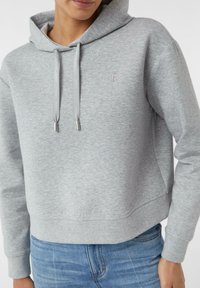 Grauer Hoodie mit lockerer Passform, texturiertem Stoff, Kordelzügen mit Metallenden und einem kleinen gestickten Logo auf der Brust.