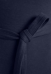 Navyblauw geribbeld katoen met een strikceintuur, met een gladde textuur en een veilige knoop in de taille, wat een getailleerde uitstraling creëert.