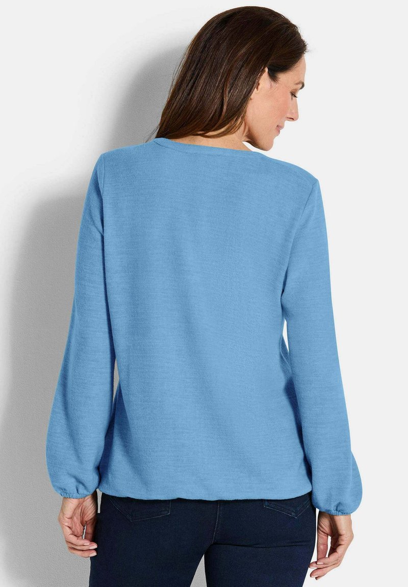 Pullover azzurro chiaro con maniche lunghe e arricciate, scollatura rotonda e vestibilità leggermente ampia, realizzato in morbido tessuto testurizzato.