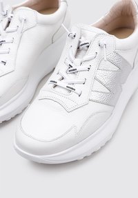 Zapatillas de piel blancas con acentos plateados texturizados, punta redonda y cordones blancos planos. Presentan un collar acolchado y una suela acolchada.