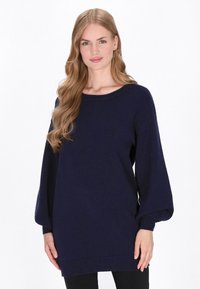 Granatowy sweter wykonany z miękkiego materiału, z szerokim dekoltem i bufiastymi rękawami. Krój jest luźny, zakrywający biodra.