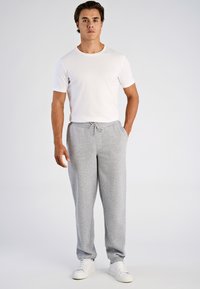 Grijze sweatpants met een taillekoord, gecombineerd met een aangesloten wit T-shirt met korte mouwen en witte sneakers. Soepele structuur, casual ontwerp.