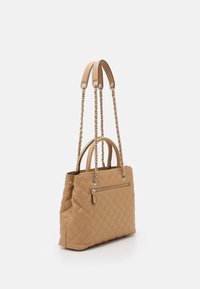 Quilted tan håndtaske med to top-håndtag, kæde-accenter og en ekstern lynlås-lomme; struktureret form, blød læderstruktur.