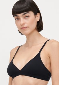 Black triangle bralette with thin adjustable straps, soft fabric, and a seamless design. No embellishments or patterns visible.