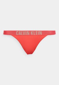 Κόκκινο γυναικείο στρινγκ με φαρδιά ελαστική μέση που έχει μεγάλο μπεζ λογότυπο Calvin Klein στο μπροστινό μέρος.
