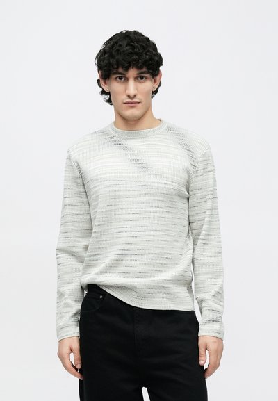 Gaiši pelēks garroku džemperis ar teksturētu horizontālu svītru rakstu; apaļa kakla izgriezums un piegulošas piedurknes. Valkāts ar melnām biksēm.