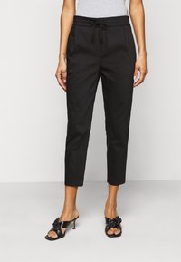 Svarta cropped byxor med dragsko i midjan, två framfickor och en len yta. Bärs med svarta klacksandaler med en rosettdetalj.