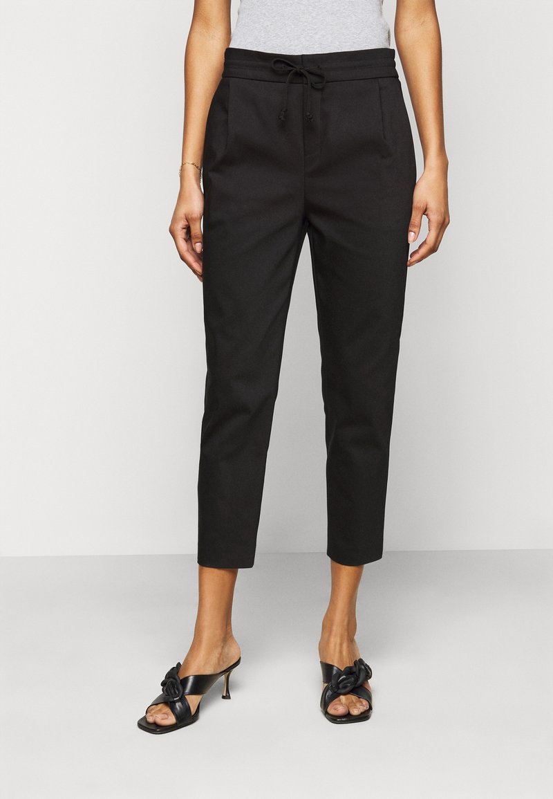 Svarta cropped byxor med dragsko i midjan, två framfickor och en len yta. Bärs med svarta klacksandaler med en rosettdetalj.