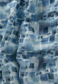 Lätt, vävd tyg med en blå gradient som har abstrakta fyrkantiga mönster i olika nyanser, vilket ger en texturerad effekt.