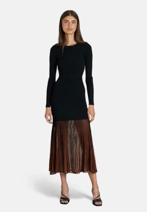Robe noire à manches longues côtelées avec une jupe en tulle brun plissée. Présente un corsage ajusté et une section inférieure fluide et texturée.